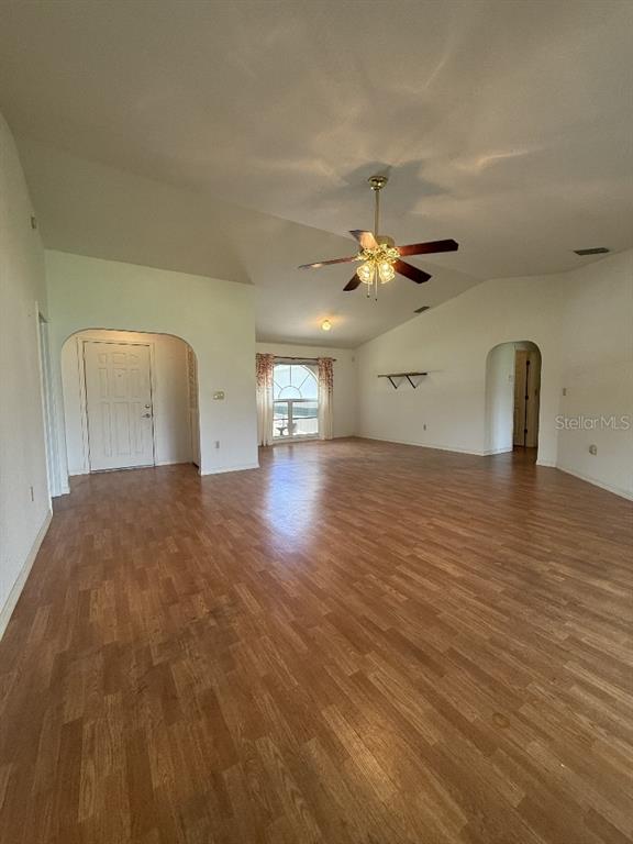 A spacious living room features wood-look flooring, a vaulted ceiling with a fan, and arched doorways — 64 NORMAN STREET, PORT CHARLOTTE, FL