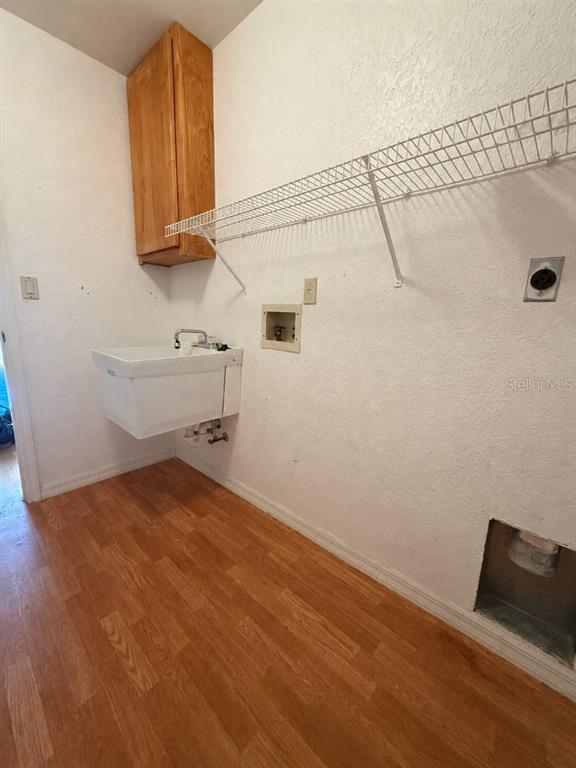 A laundry room features a utility sink, a wall-mounted cabinet, wire shelving, and wood-look flooring — 64 NORMAN STREET, PORT CHARLOTTE, FL