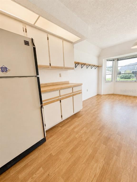A kitchen area features white cabinets, a light wood countertop, a refrigerator, and wood-look flooring — 64 NORMAN STREET, PORT CHARLOTTE, FL