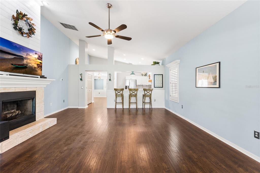 A kitchen with white cabinets, stainless steel appliances, and dark wood flooring under a vaulted ceiling — 19218 SEA MIST LANE, LUTZ, FL