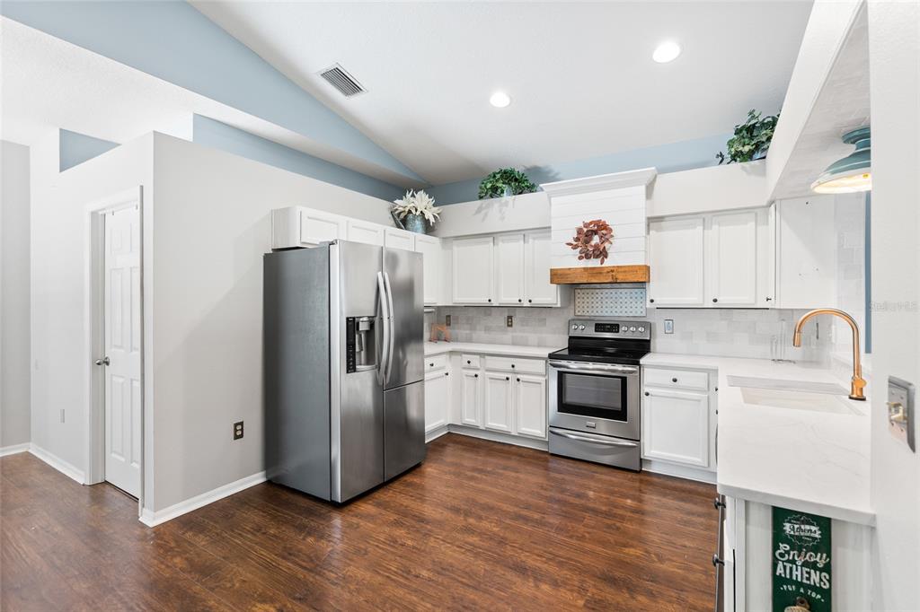 A kitchen with a breakfast bar and three wooden stools opens into a dining area — 19218 SEA MIST LANE, LUTZ, FL