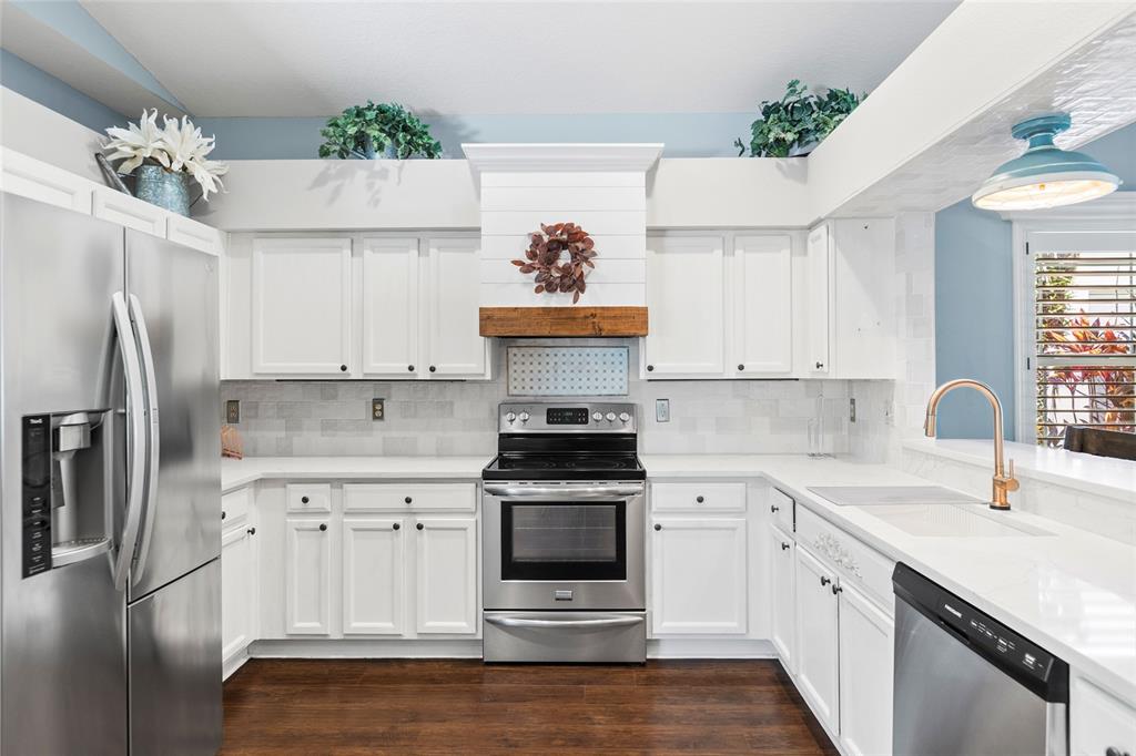 A dining area features dark wood floors, white wainscoting, plantation shutters, and a light fixture — 19218 SEA MIST LANE, LUTZ, FL