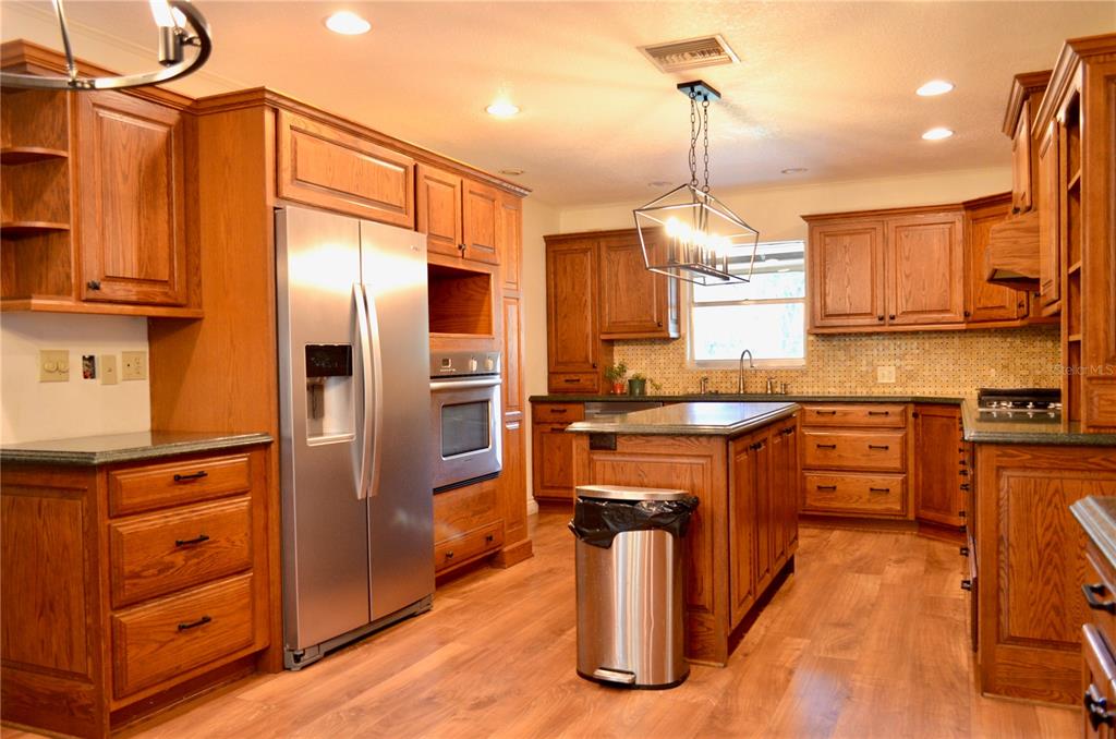 A kitchen with wood cabinets, a central island, and a large circular chandelier — 308 N SALISBURY AVENUE, DELAND, FL