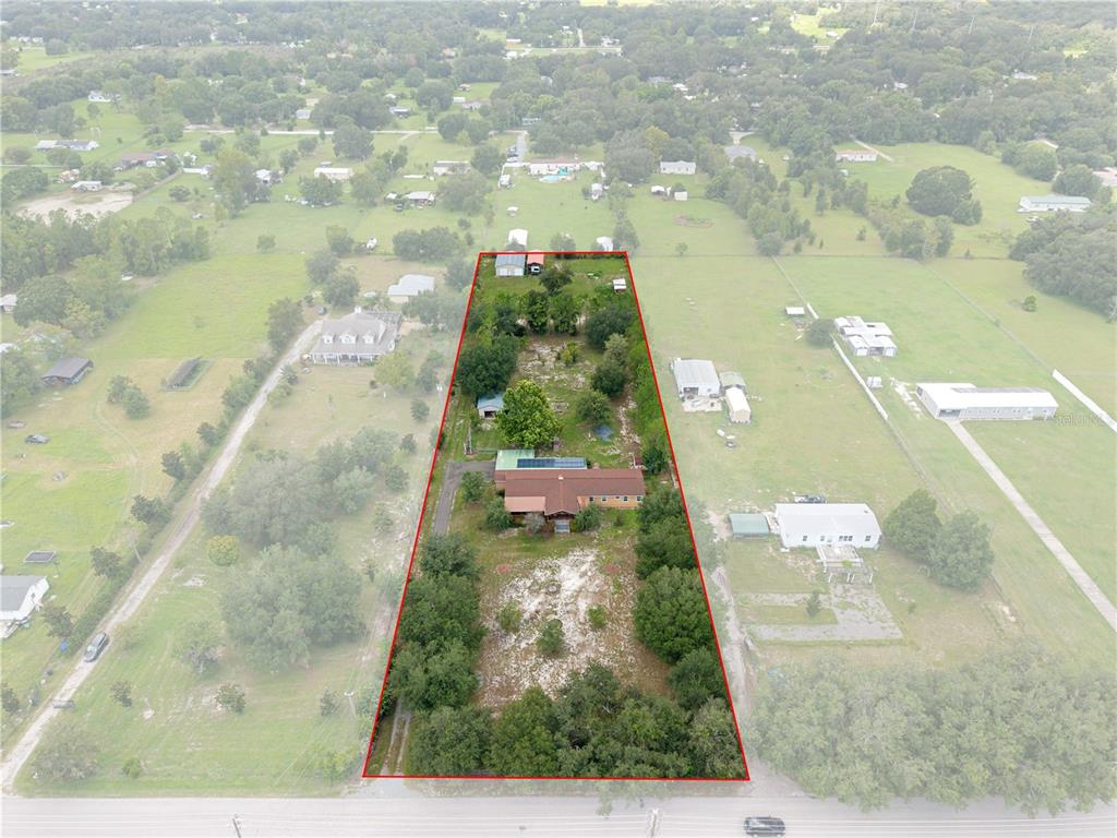 An aerial view shows a house and several outbuildings on a long, rectangular, tree-lined lot — 4235 ALLEN ROAD, ZEPHYRHILLS, FL