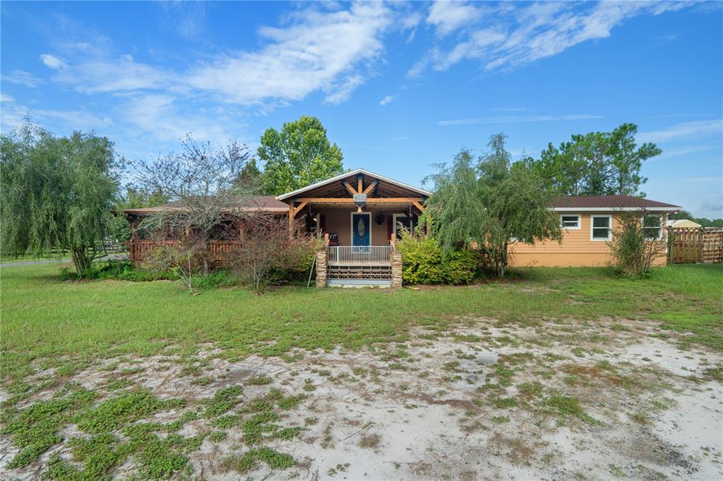A single-story house with a covered porch, wooden siding, and a large front yard — 4235 ALLEN ROAD, ZEPHYRHILLS, FL