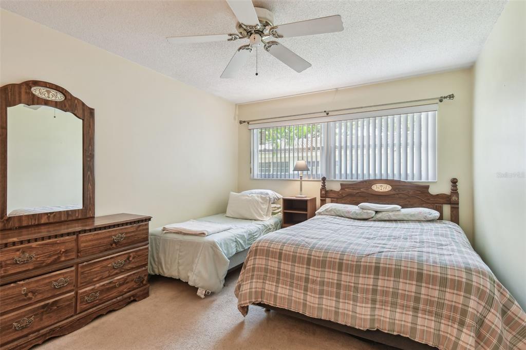 A bedroom features a double bed, a single bed, a wooden dresser, and a ceiling fan — 11200 102ND AVENUE UNIT 48, SEMINOLE, FL