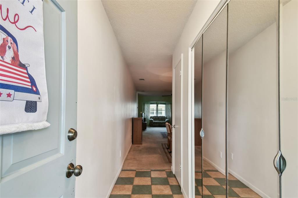 A hallway with checkered tile flooring leads to a living area with carpeted floors — 11200 102ND AVENUE UNIT 48, SEMINOLE, FL