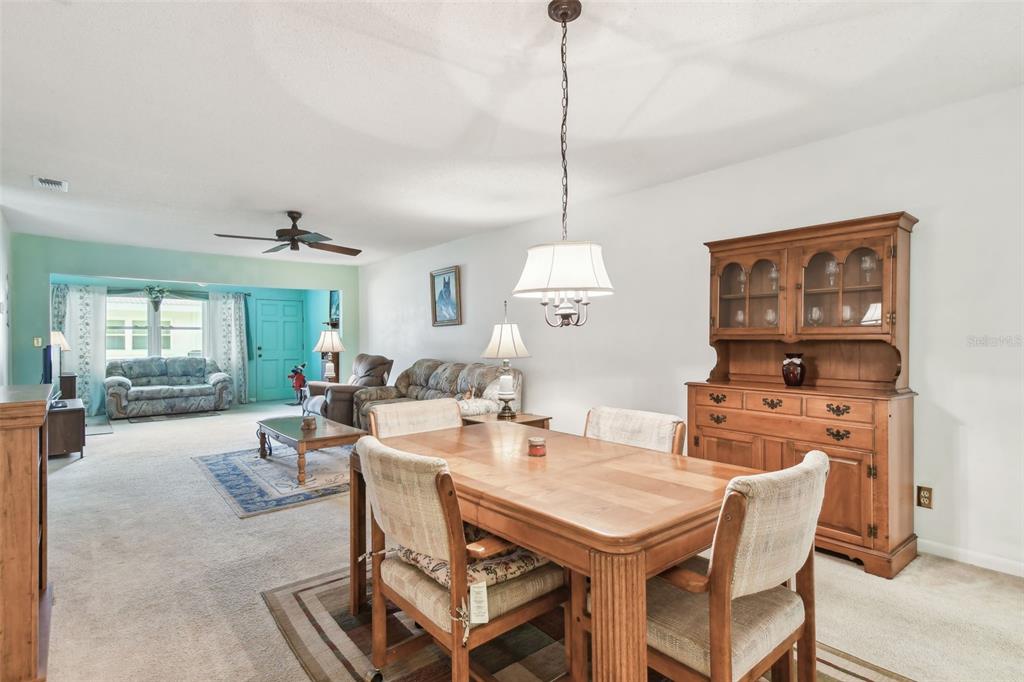 A dining area with a wooden table and hutch opens into a carpeted living room — 11200 102ND AVENUE UNIT 48, SEMINOLE, FL