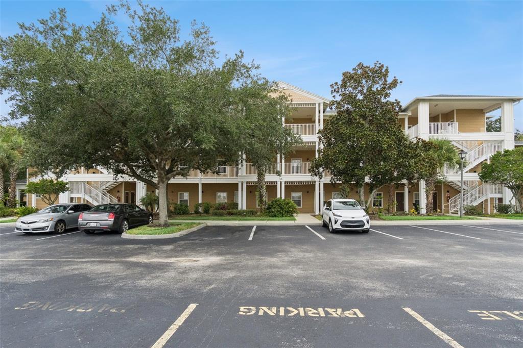 A three-story apartment building with beige siding and white balconies sits behind a parking lot — 504 RUM RUN, DAVENPORT, FL