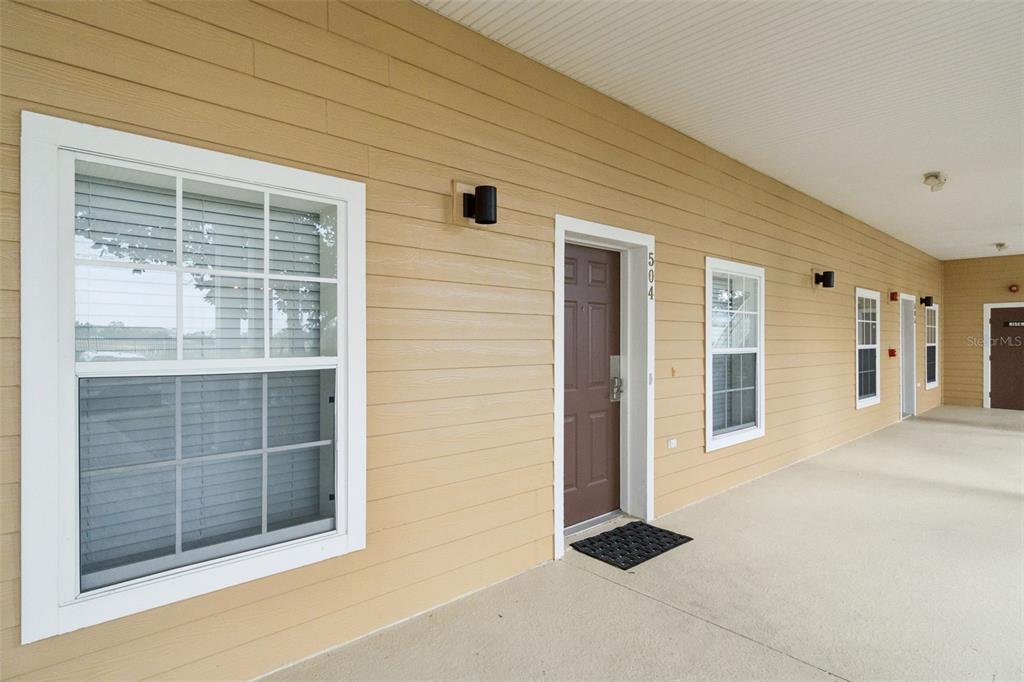A tan-sided building exterior features a brown front door labeled 504 and multiple windows — 504 RUM RUN, DAVENPORT, FL