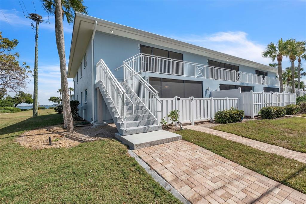 A two-story light blue building features an exterior staircase leading to a second-floor balcony — 600 MANATEE AVENUE UNIT 145, HOLMES BEACH, FL