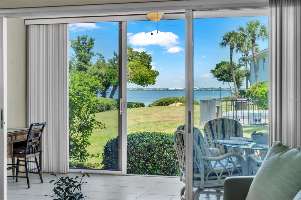 A view through sliding glass doors shows a patio, grassy lawn, and a waterfront bay — 600 MANATEE AVENUE UNIT 145, HOLMES BEACH, FL