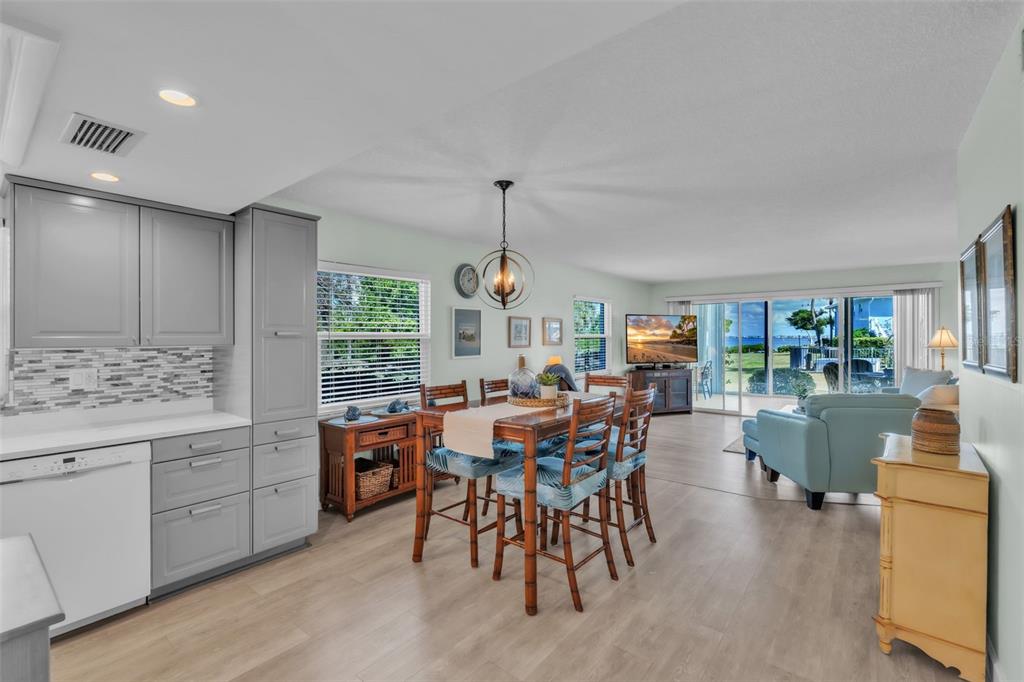 An open-concept dining area and living room with light wood floors and a view outdoors — 600 MANATEE AVENUE UNIT 145, HOLMES BEACH, FL