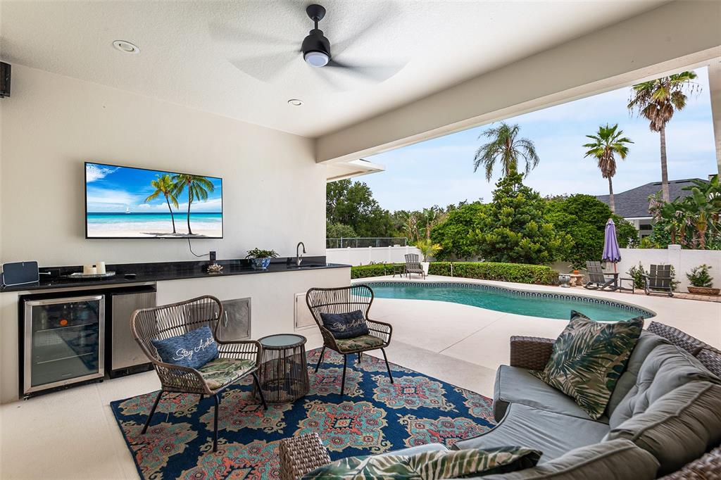 A screened-in patio features a kidney-shaped swimming pool and a covered outdoor seating area — 902 HANOVER WAY, LAKELAND, FL