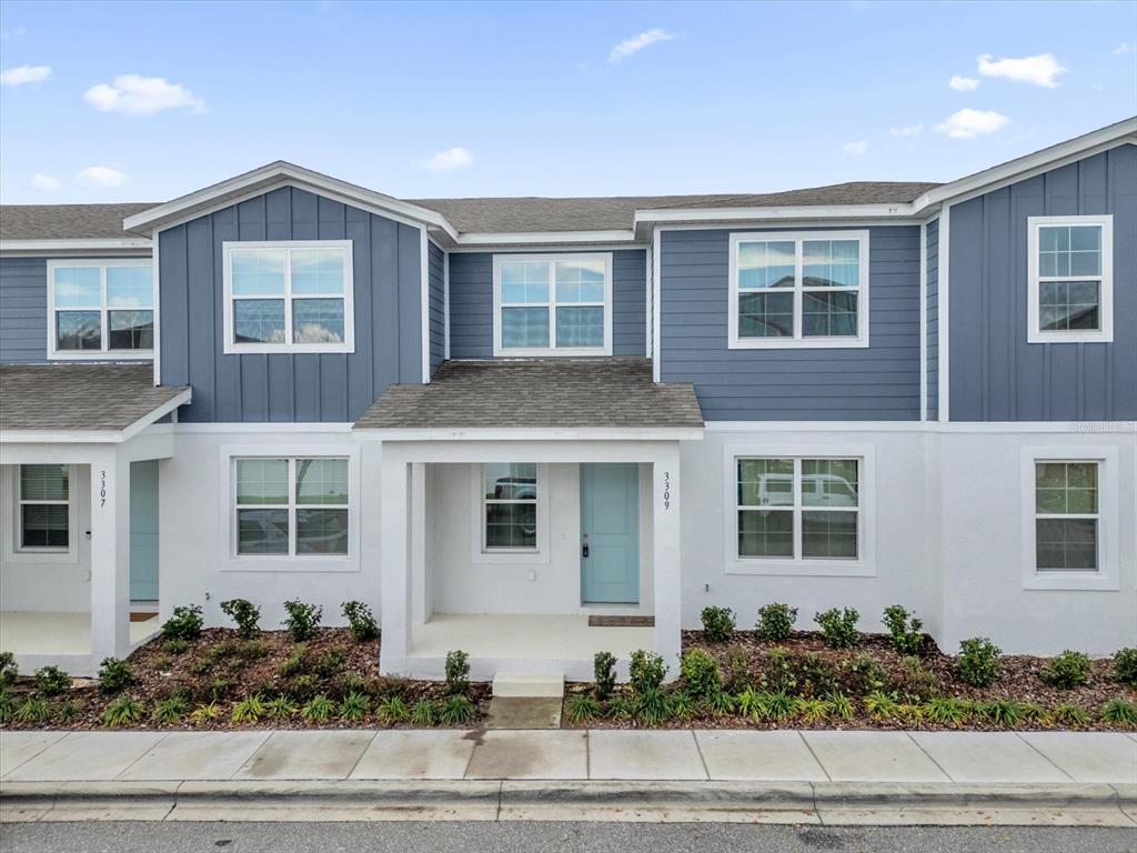 A two-story townhouse exterior features blue siding, white stucco, and a light blue front door — 3309 GRANDE HERON DRIVE, ST CLOUD, FL
