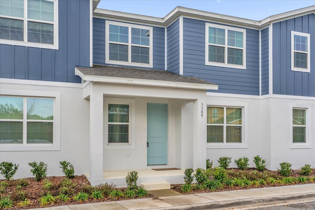 The exterior of a two-story townhouse features blue siding, white stucco, and a light blue door — 3309 GRANDE HERON DRIVE, ST CLOUD, FL