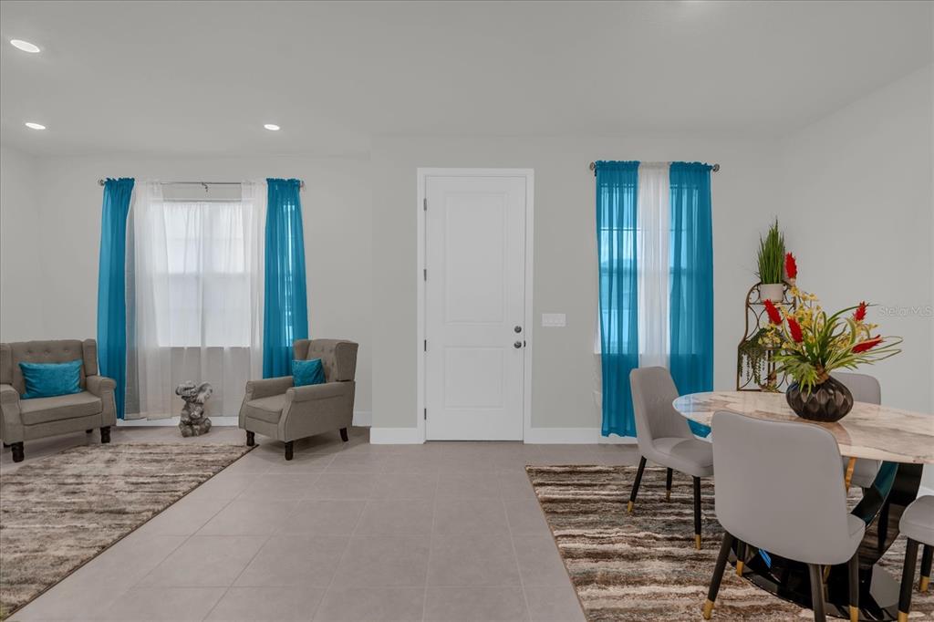 A room with gray tile floors, two armchairs, and a dining table with chairs — 3309 GRANDE HERON DRIVE, ST CLOUD, FL