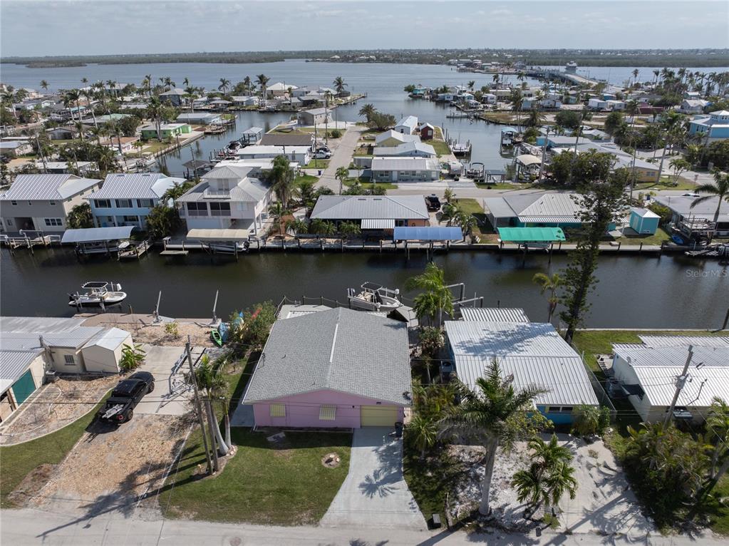 An aerial view shows a pink house with a gray roof situated along a canal — 11476 MAY STREET, MATLACHA, FL