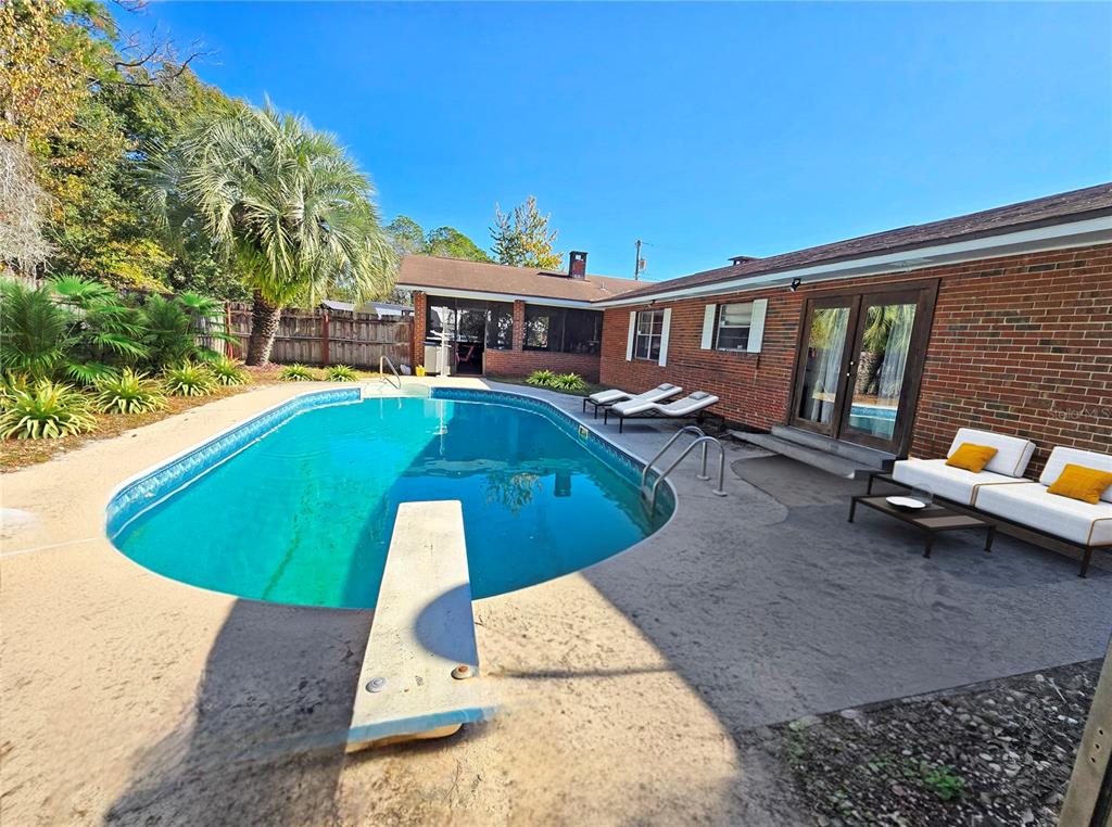 A brick house exterior features a swimming pool with a diving board and patio furniture — 12046 US-301, HAMPTON, FL