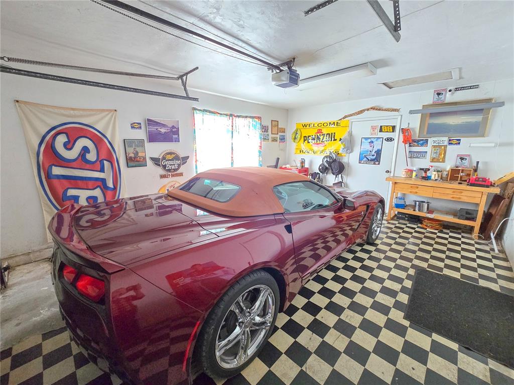 A maroon convertible car is parked in a garage with checkered flooring and wall decor — 12046 US-301, HAMPTON, FL