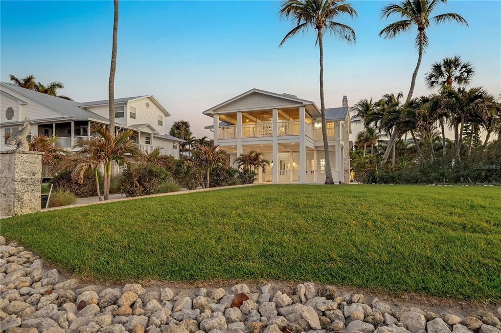 A two-story white house with a large porch stands behind a grassy lawn — 8241 MAIN STREET, BOKEELIA, FL