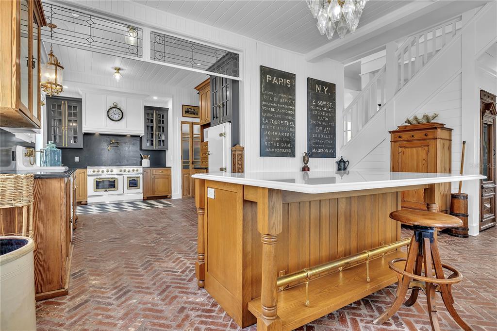 A kitchen features a brick floor, a wooden island with a white countertop, and dark cabinetry — 8241 MAIN STREET, BOKEELIA, FL