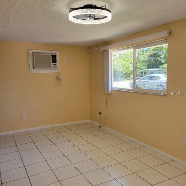 A room with light yellow walls, white tile flooring, a ceiling fan, and a window — 7431 SHEEPSHEAD DRIVE, HUDSON, FL