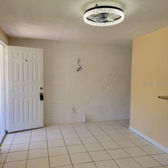 An interior room features a white brick wall, tiled flooring, and a modern ceiling fan light — 7431 SHEEPSHEAD DRIVE, HUDSON, FL