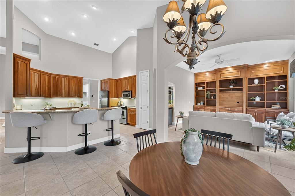 An open-concept kitchen and living area with wood cabinetry, tile flooring, and a chandelier — 2816 N PRESTWICK WAY, LECANTO, FL