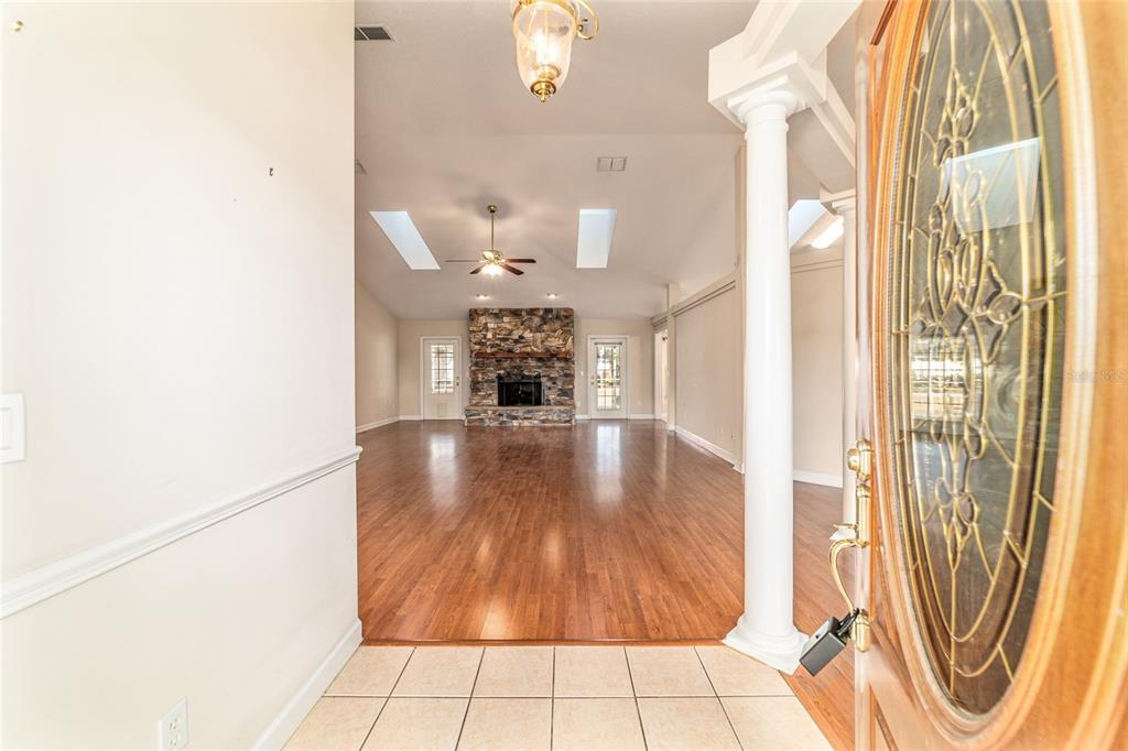 An entryway with tile flooring opens into a living room featuring hardwood floors and stone fireplace — 9611 SW 45TH AVENUE, OCALA, FL