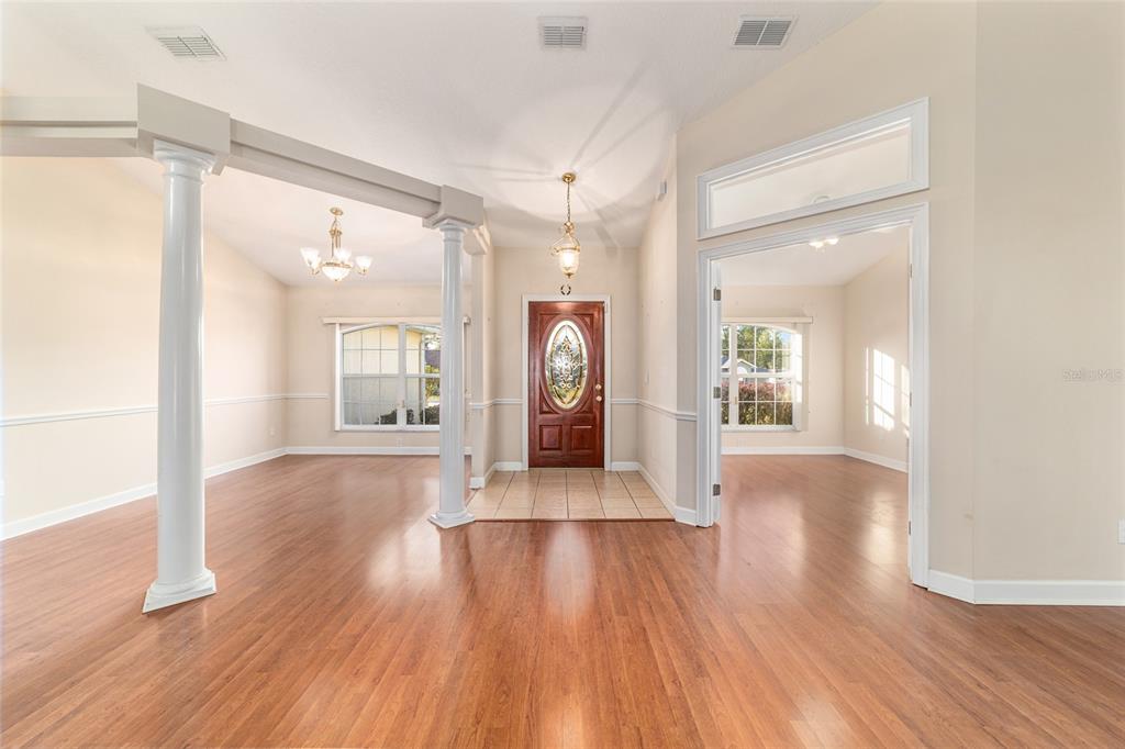 An entryway with wood flooring, two white columns, and a wooden front door with glass — 9611 SW 45TH AVENUE, OCALA, FL