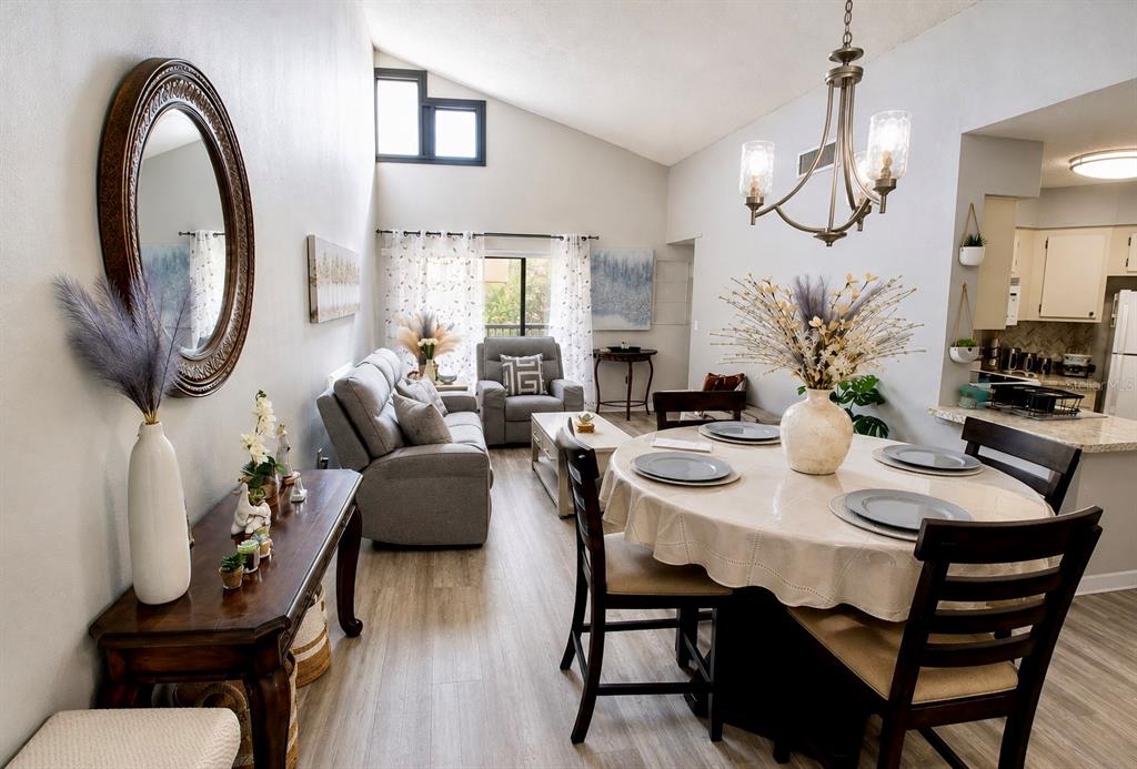 An open-concept living and dining area features vaulted ceilings, light wood flooring, and neutral decor — 3712 SOUTHPOINTE DRIVE UNIT U6, ORLANDO, FL