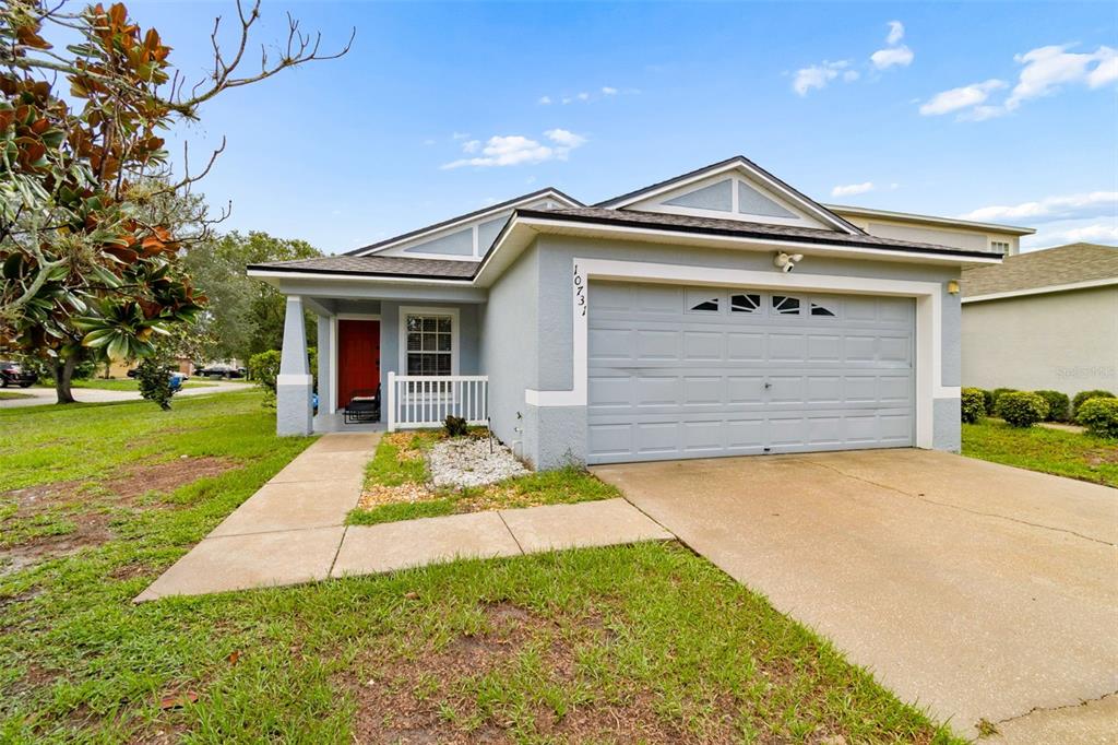 A single-story house with a light blue exterior, a red front door, and a two-car garage — 10731 NAVIGATION DRIVE, RIVERVIEW, FL