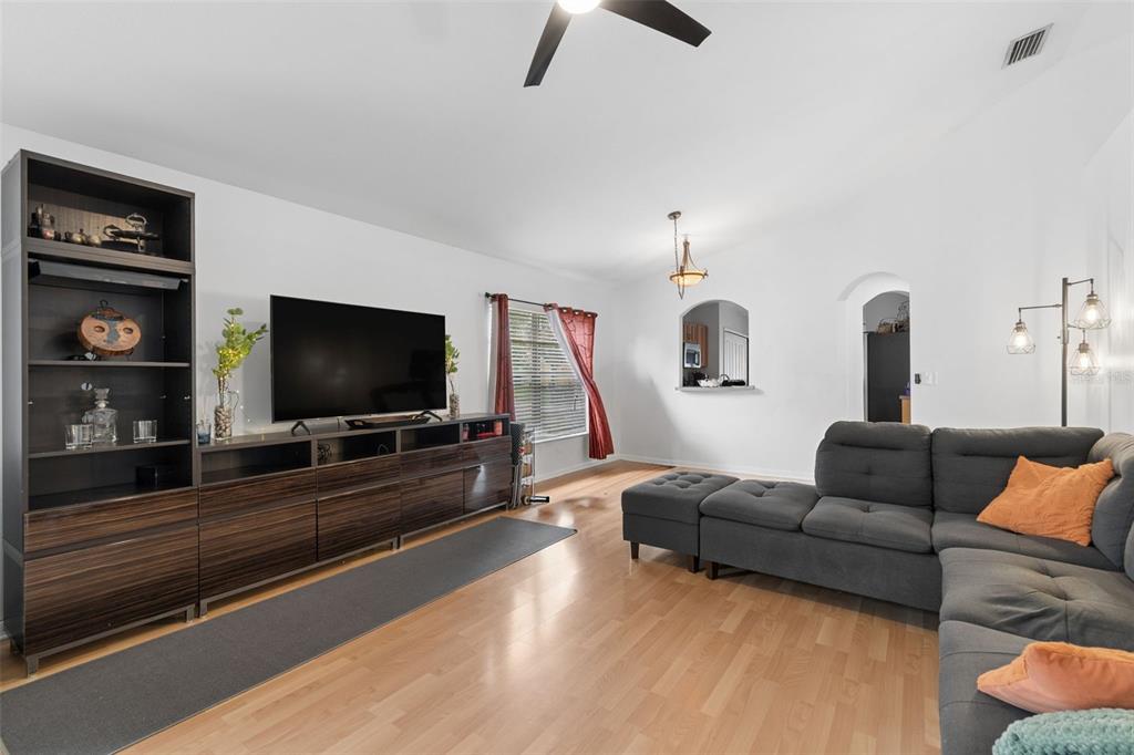 A living room features a dark wood entertainment center, a gray sectional sofa, and hardwood floors — 10731 NAVIGATION DRIVE, RIVERVIEW, FL
