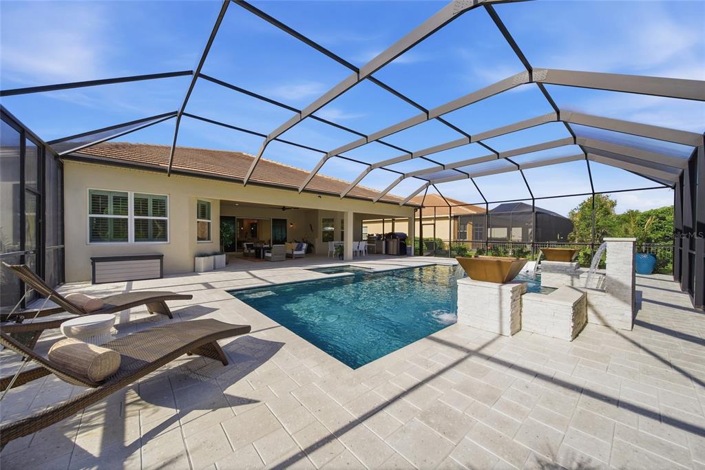 A screened-in patio features a swimming pool with water features and lounge chairs — 2420 COCO PALM CIRCLE, WESLEY CHAPEL, FL