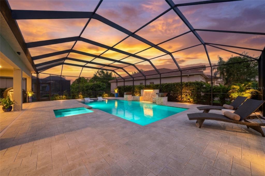A screened-in patio features a swimming pool, a hot tub, and lounge chairs at sunset — 2420 COCO PALM CIRCLE, WESLEY CHAPEL, FL