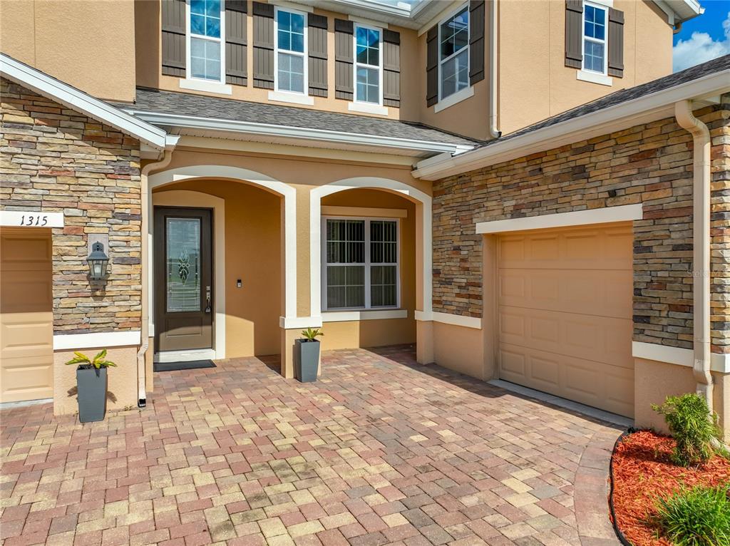 A two-story suburban house with a stone facade, tan stucco, and a brick paver driveway — 1315 DUSTY PINE DRIVE, APOPKA, FL