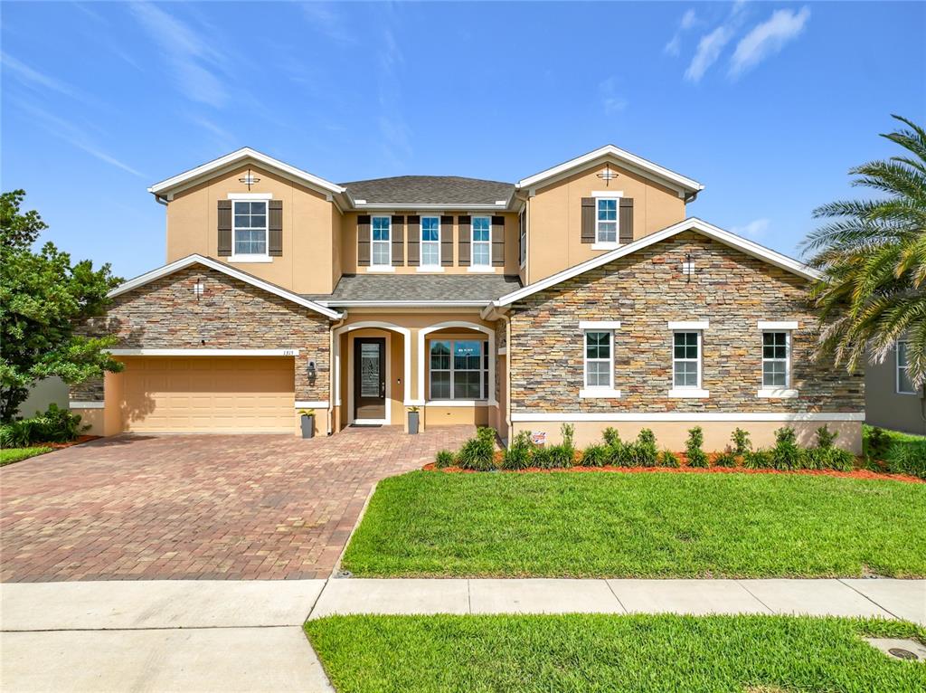 The exterior of a two-story home features stone veneer, a paver driveway, and a garage — 1315 DUSTY PINE DRIVE, APOPKA, FL