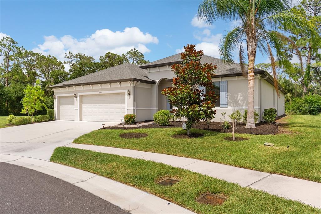 A single-story house with a beige stucco exterior, a three-car garage, and a landscaped yard — 3918 GAVIOTA DRIVE, RUSKIN, FL
