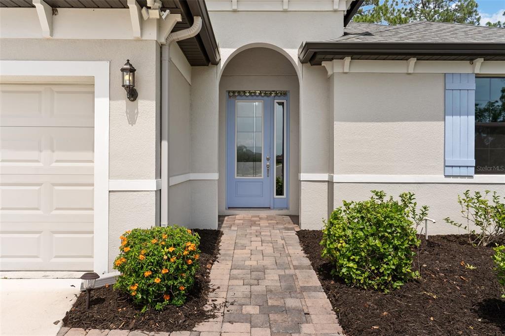 A light blue front door sits under an arched entryway with a stone paver walkway — 3918 GAVIOTA DRIVE, RUSKIN, FL