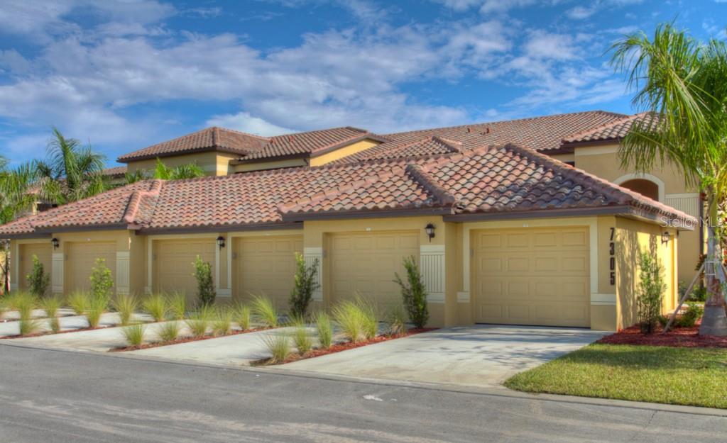 A row of attached garages with tan stucco walls and terracotta tile roofs — 7305 RIVER HAMMOCK DRIVE UNIT 206, BRADENTON, FL