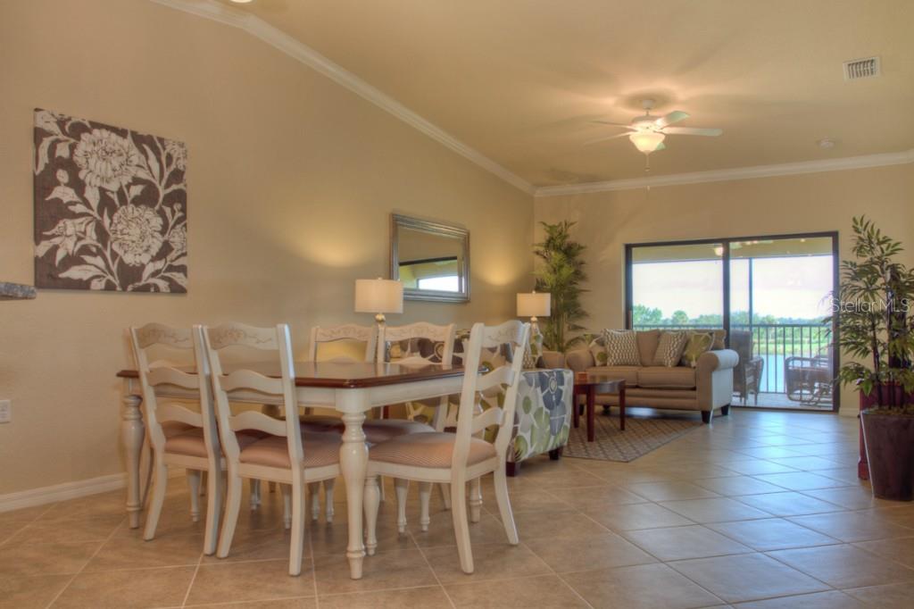 A dining area with a wooden table and chairs opens into a living room with tile — 7305 RIVER HAMMOCK DRIVE UNIT 206, BRADENTON, FL