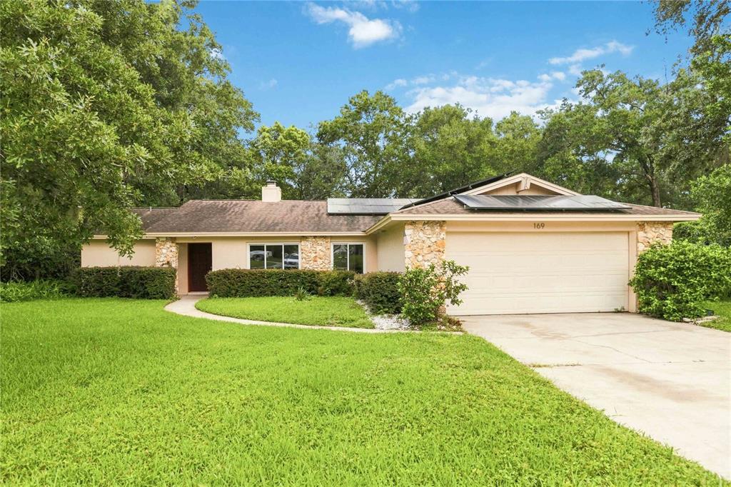 A single-story house with a stone facade, a two-car garage, and solar panels on the roof — 169 DUNCAN TRAIL, LONGWOOD, FL