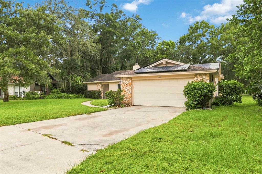A single-story house with a stone facade, a two-car garage, and solar panels on the roof — 169 DUNCAN TRAIL, LONGWOOD, FL