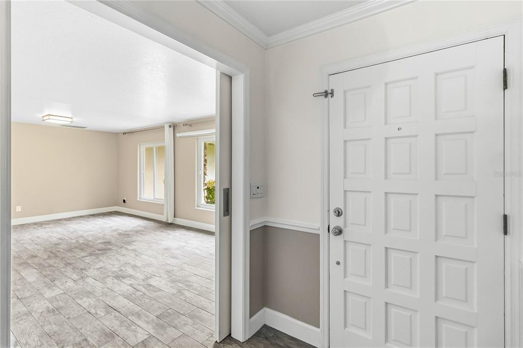 A white front door opens into a room with light-colored wood-look tile flooring — 169 DUNCAN TRAIL, LONGWOOD, FL