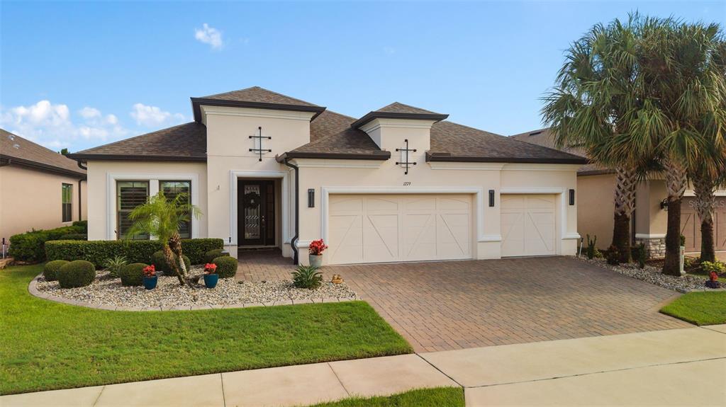 A single-story house with a beige stucco exterior, a three-car garage, and a paved driveway — 1279 ZEEK RIDGE STREET, CLERMONT, FL