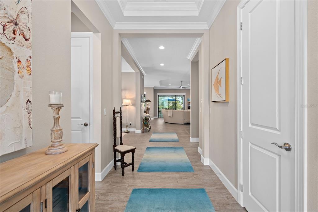 A bright hallway with light wood-look tile flooring leads toward an open living area — 1279 ZEEK RIDGE STREET, CLERMONT, FL