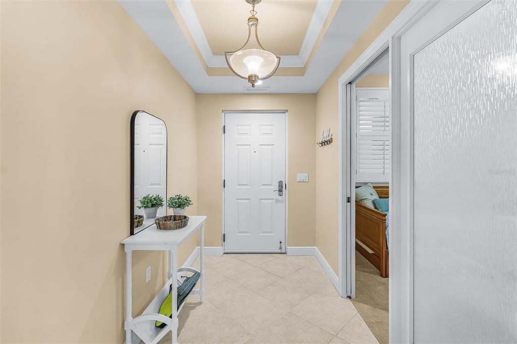 A bright entryway features a white console table, a wall mirror, and a tray ceiling — 3321 SUNSET KEY CIRCLE UNIT 508, PUNTA GORDA, FL