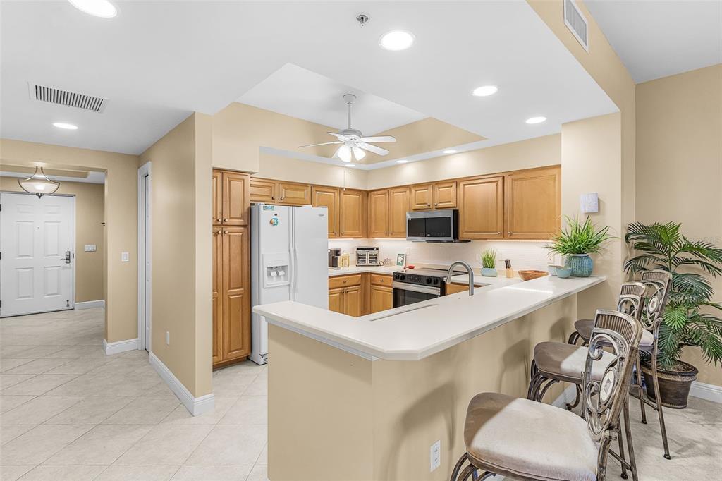 A kitchen features light wood cabinets, white countertops, a breakfast bar, and tile flooring — 3321 SUNSET KEY CIRCLE UNIT 508, PUNTA GORDA, FL