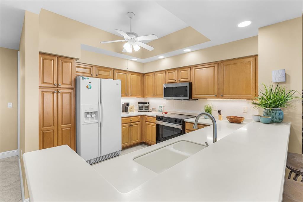 A kitchen with light wood cabinets, white countertops, a white refrigerator, and a ceiling fan — 3321 SUNSET KEY CIRCLE UNIT 508, PUNTA GORDA, FL